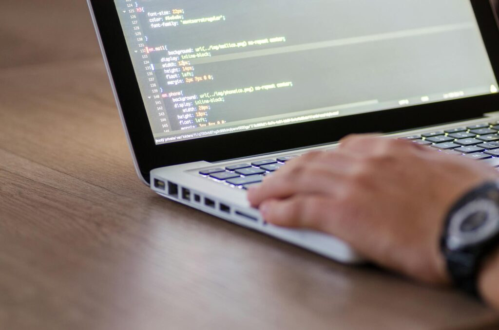 Person coding HTML on a laptop representing hands-on website design work for beginners learning web development