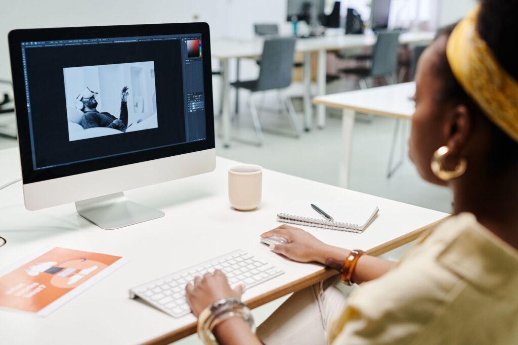 Woman editing visuals on a computer in a modern office while choosing the right image creation provider